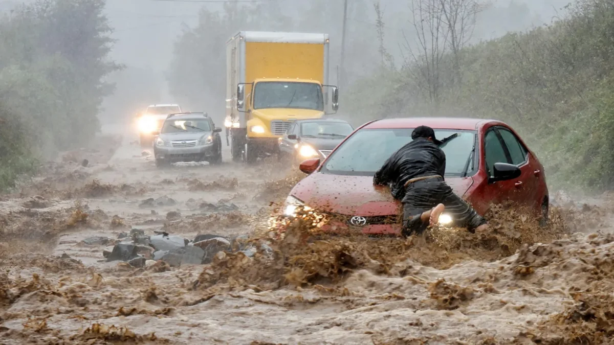 A local resident helps free a car that became stranded in a stretch of flooding road on the outskirts of Boone, North Carolina
