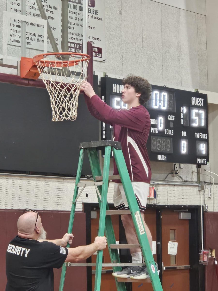 Senior Jack McCoy cutting down the net after one of the last games in the current Connie Donahue gym.